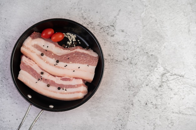 Kostenloses Foto schweinebauch in einer pfanne mit pfeffersamen tomaten und gewürzen