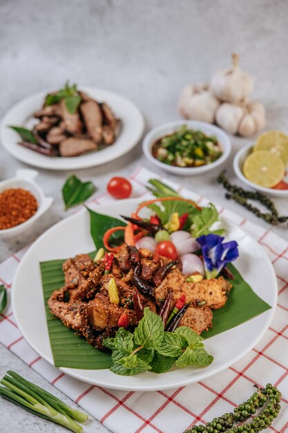 Schweinefleisch Nam Tok mit gebratenem Chili, Tomate, Limette, Gurke und frischem Pfeffer. Thai Essen.