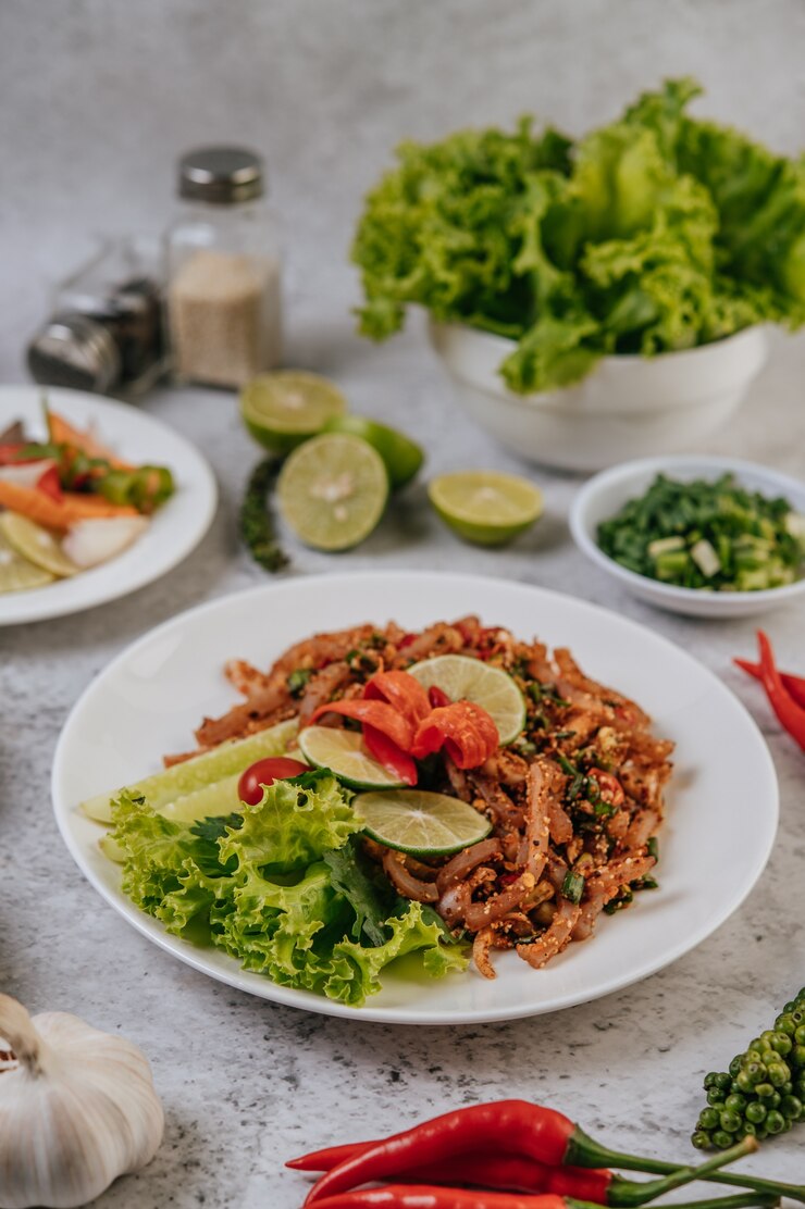 Kostenlose Foto schweinehaut larb mit karotten, gurken, limetten, frühlingszwiebeln, chili, frisch gemahlenem pfeffer und salat.