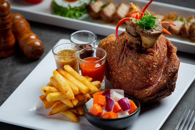 Schweinshaxe auf Deutsch mit Soßen auf dunklem Hintergrund