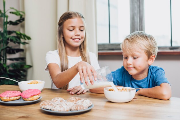 Schwester gießt Milch für ihren Bruder ein