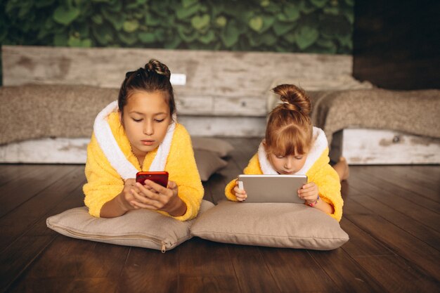 Schwestern, die auf Boden mit Telefon und Tablette liegen