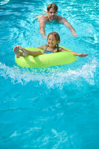 Schwimmbad. Junger Mann mit gelbem Schlauch in einem Schwimmbad