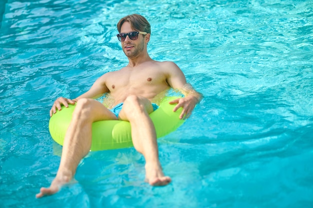 Schwimmbad. Junger Mann mit gelbem Schlauch in einem Schwimmbad