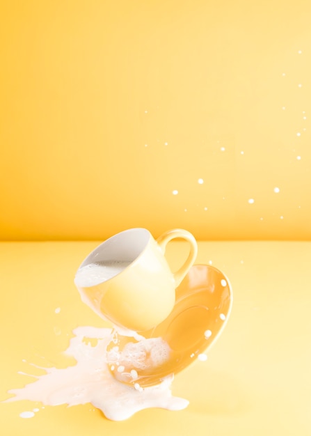 Schwimmende gelbe Tasse mit verschütteter Milch