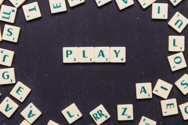 Scrabble-Buchstaben über schwarzem Hintergrund spielen