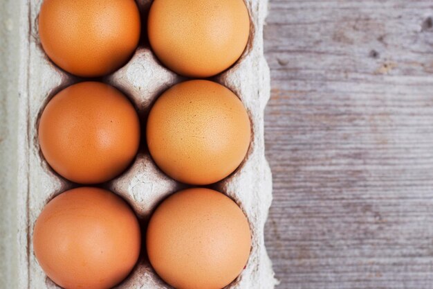 Sechs frische braune eier in der kiste auf grauer holztisch-draufsicht