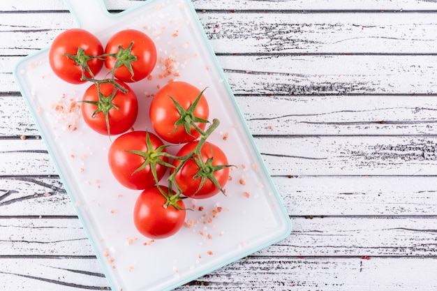 Kostenloses Foto seesalz und bündel tomaten auf weißer schneidebrettlebensmittelart