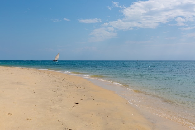 Segelboot auf dem ruhigen Ozean durch den Sandstrand gefangen genommen in Sansibar, Afrika