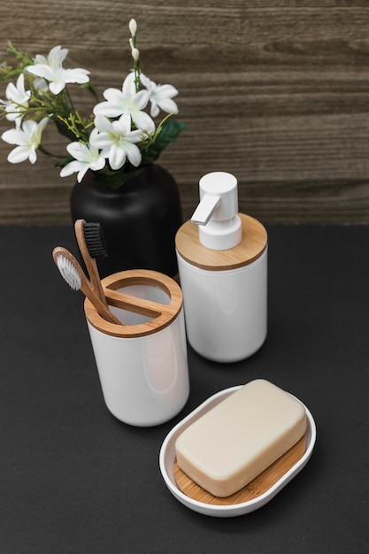 Seife; Zahnbürste; Kosmetikflasche und Vase mit weißer Blume auf Tischplatte