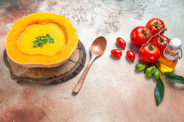 Seite nahaufnahme ansicht einer suppe kürbissuppe auf dem brettlöffel öl zitrusfrucht tomaten