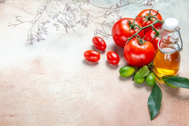 Seite Nahaufnahme Ansicht Tomaten Flasche Öl Zitrusfrüchte mit Blättern Tomaten mit Stielen