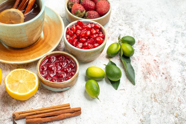 Seite Nahaufnahme Beeren und Tee eine Tasse Tee Limetten Marmelade Granatapfel Erdbeeren und Zimt