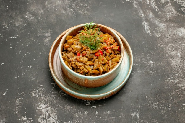 Seite Nahaufnahme Schüssel mit grünen Bohnen grüne Bohnen mit Tomaten in Schüssel auf einem Tablett auf der dunklen Oberfläche