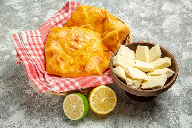 Seite Nahaufnahme Torten und Zitronen Teller mit Käse Zitrone und Limette neben dem Holzkorb mit appetitlichen Torten und Tischdecke auf grauem Hintergrund