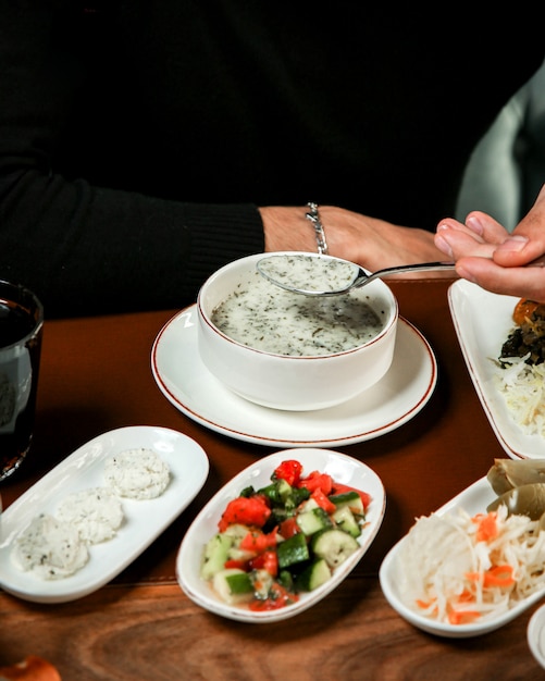 Seite vie der traditionellen aserbaidschanischen Joghurtsuppe Dovga in einer weißen Schüssel mit Pita auf dem Tisch
