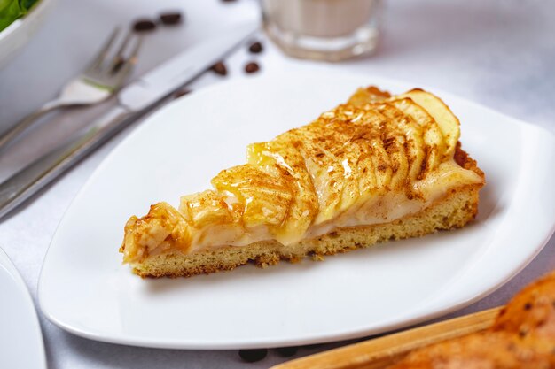 Seitenansicht Apfelkuchen mit Sahne und Zimt auf einem Teller