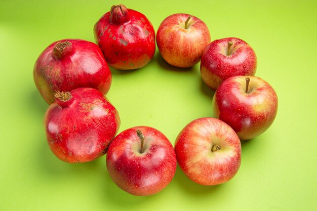 Seitenansicht aus der Ferne Früchte rote reife Granatäpfel und Äpfel auf der grünen Oberfläche
