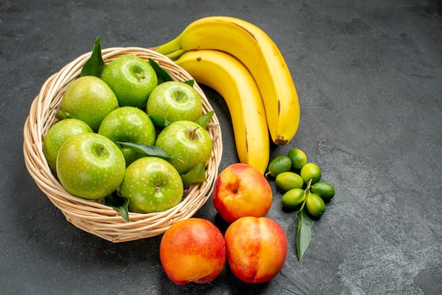 Seitenansicht aus der Ferne Früchte Zitrusfrüchte Bananen Äpfel im Korb Nektarinen auf dem Tisch