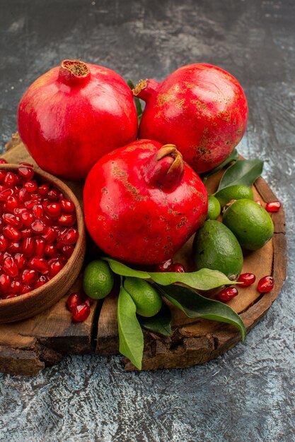 Seitenansicht aus der Ferne Granatäpfel drei Granatapfel mit Samen in Schüssel auf dem Holzbrett