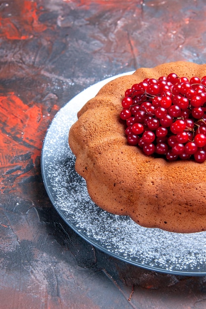 Kostenloses Foto seitenansicht aus der ferne leckerer kuchenkuchen mit beeren auf dem teller auf der rot-blauen fläche