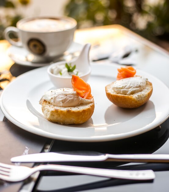 Seitenansicht Brötchen mit Butter und rotem Fisch auf einem Teller mit Sauce