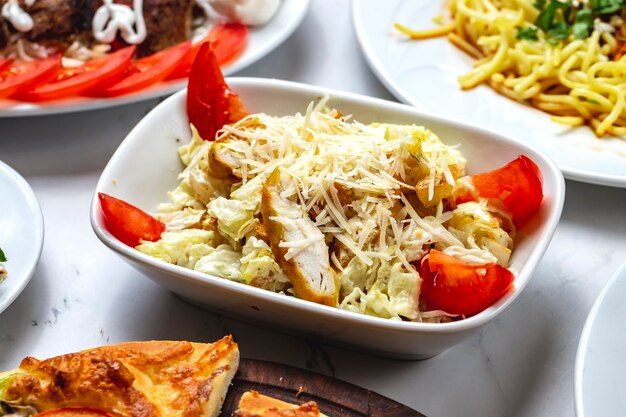 Seitenansicht Caesar Salat gegrilltes Hähnchenfilet Tomatensalat und Parmesan auf einem Brett