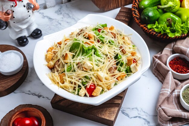 Seitenansicht Caesar Salat mit Huhn in einem Teller mit Kirschtomaten