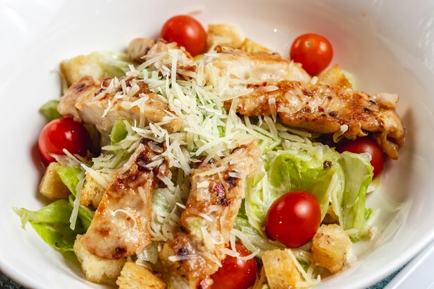 Seitenansicht Caesar Salat mit Kirschtomaten Parmesan gegrilltes Huhn und Salat auf einem Teller