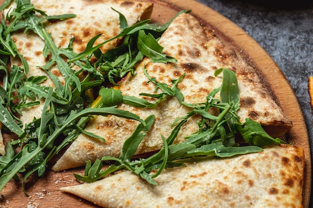 Seitenansicht Calzone Pizza geschmolzener Käse Parmesan und Rucola auf dem Tisch