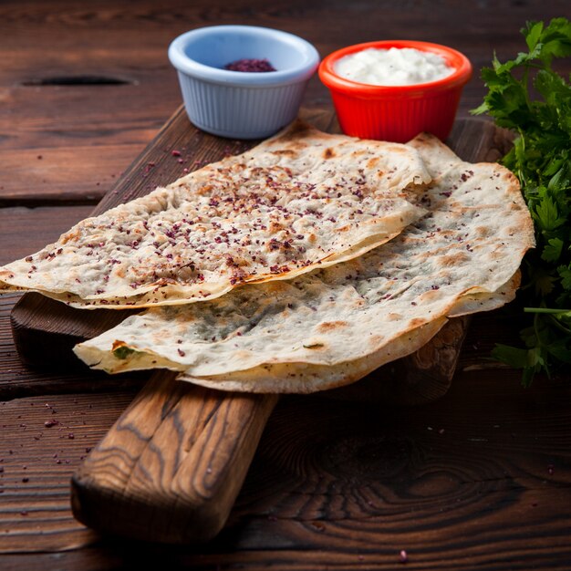 Seitenansicht Chebureks Kutab gebratene Chebureks mit Käse, Kräutern, Fleisch mit Sauce auf einem dunklen Holztisch