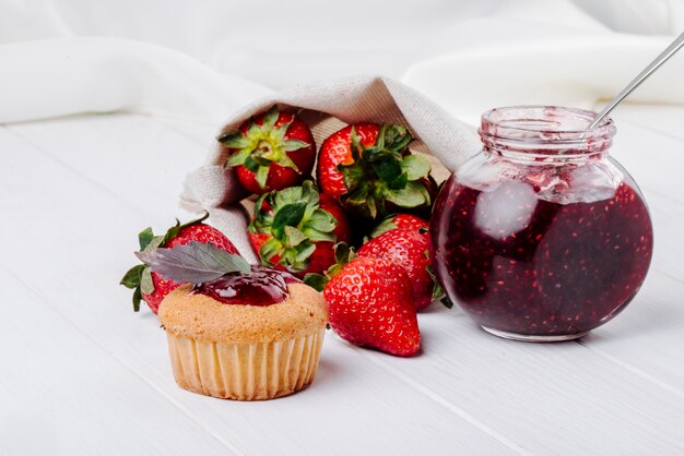 Seitenansicht Cupcake mit Erdbeermarmeladenbasilikum und frischer Erdbeermarmelade auf weißem Hintergrund