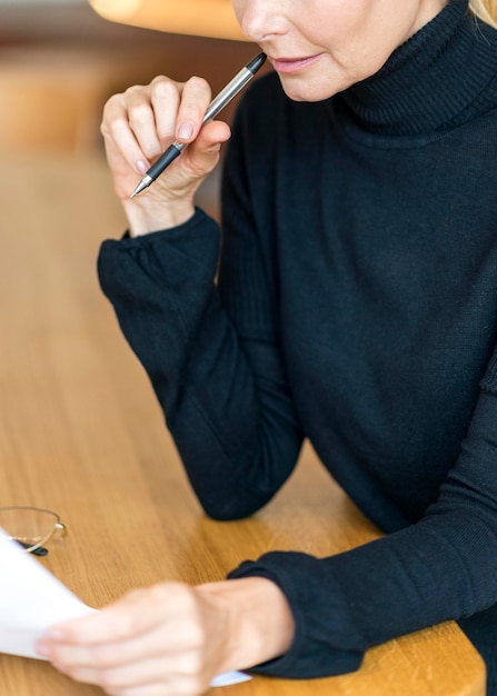 Seitenansicht der älteren Frau bei der Arbeit, die Papiere liest