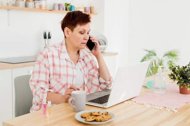 Seitenansicht der älteren Frau, die zu Hause am Telefon spricht