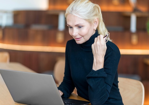 Seitenansicht der älteren Frau mit Brille, die am Laptop arbeitet