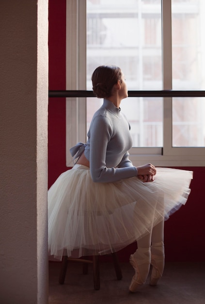 Seitenansicht der Ballerina im Tutu-Rock neben dem Fenster