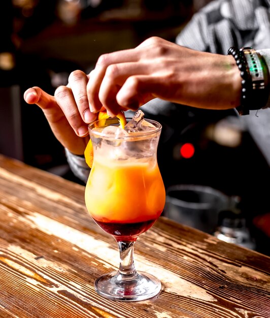 Seitenansicht Der Barkeeper macht einen Cocktail mit Orangenschalen-Dekor