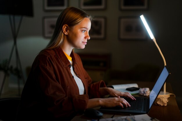 Seitenansicht der blonden Frau, die am Laptop arbeitet