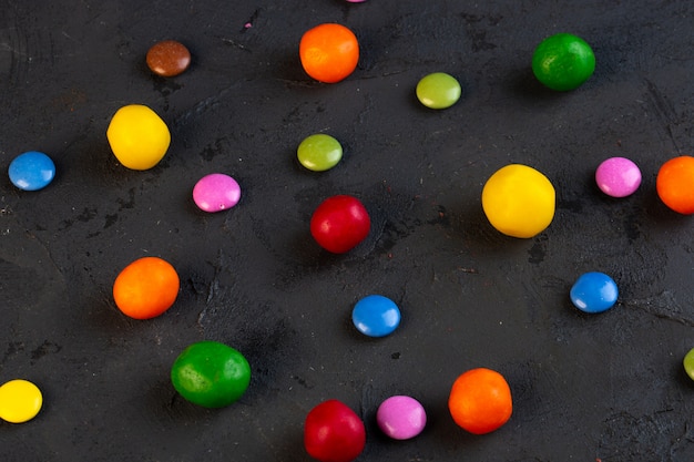 Kostenloses Foto seitenansicht der bunten bonbons auf schwarz verstreut