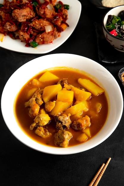 Seitenansicht der chinesischen Suppe mit Huhn und Kartoffeln im Teller