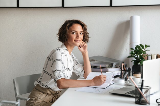 Seitenansicht der fantastischen Frau, die am Tisch sitzt