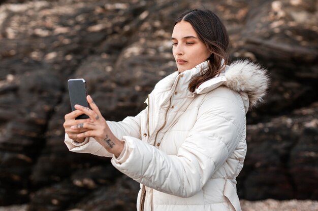 Seitenansicht der Frau am Strand, die Fotos mit Smartphone macht