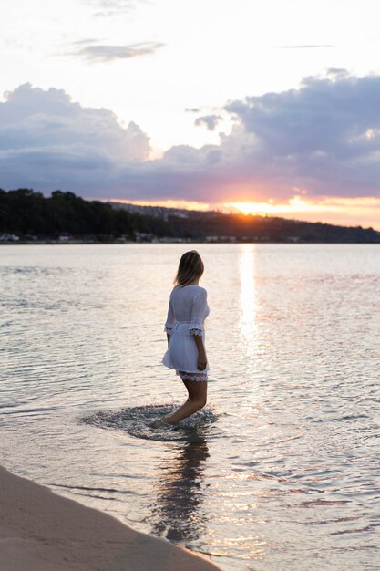 Seitenansicht der Frau, die am Strand bei Sonnenuntergang aufwirft
