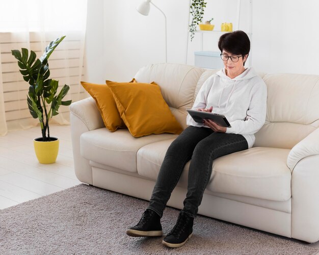 Seitenansicht der Frau, die auf Sofa mit Tablette sitzt