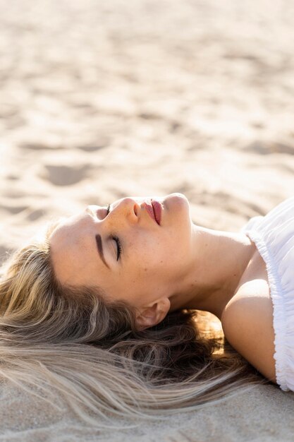 Seitenansicht der Frau, die auf Strandsand entspannt