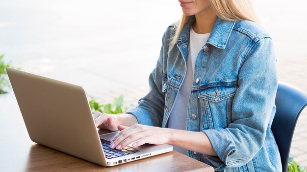 Seitenansicht der Frau, die außerhalb am Laptop arbeitet