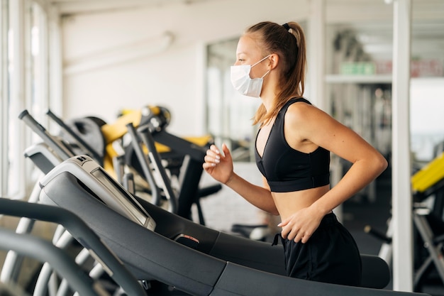 Seitenansicht der Frau, die das Laufband im Fitnessstudio verwendet