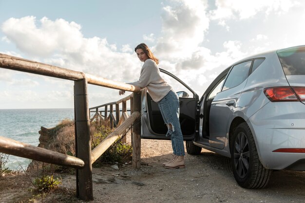 Seitenansicht der Frau, die den Blick auf den Strand von ihrem Auto genießt