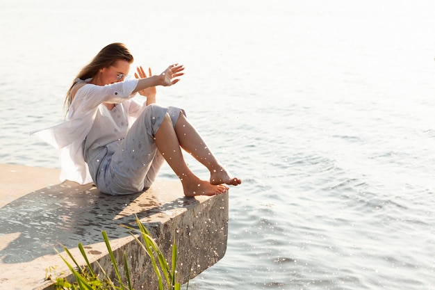 Seitenansicht der Frau, die durch Seewasser bespritzt wird