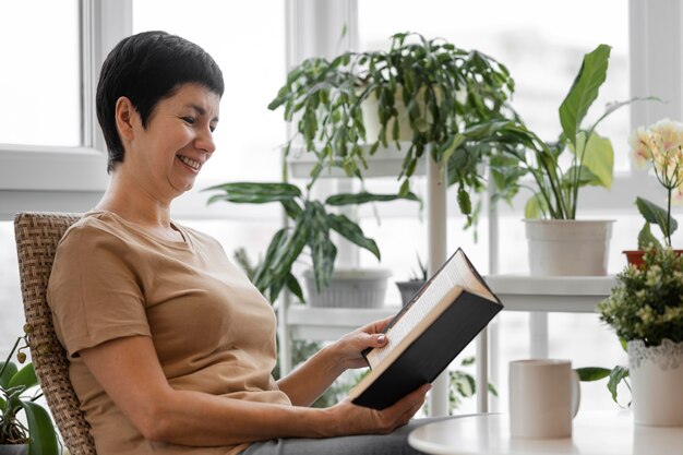 Seitenansicht der Frau, die ein Buch drinnen genießt